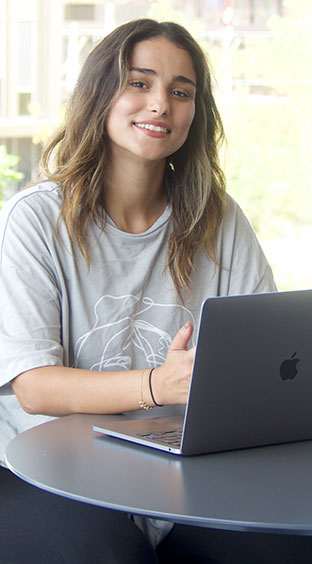 Wida sidder ved en computer og smiler